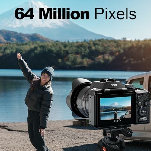 Camera displaying a woman posing by a lake with a mountain background.