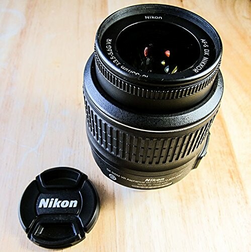 Nikon camera lens and cap on wooden table